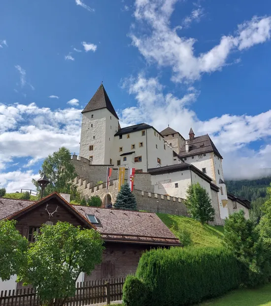 Medieval castle on a hill with tower and stone walls under blue sky in Austria